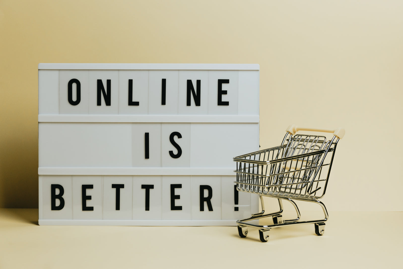Light box sign reading “Online is better!” beside a miniature shopping cart