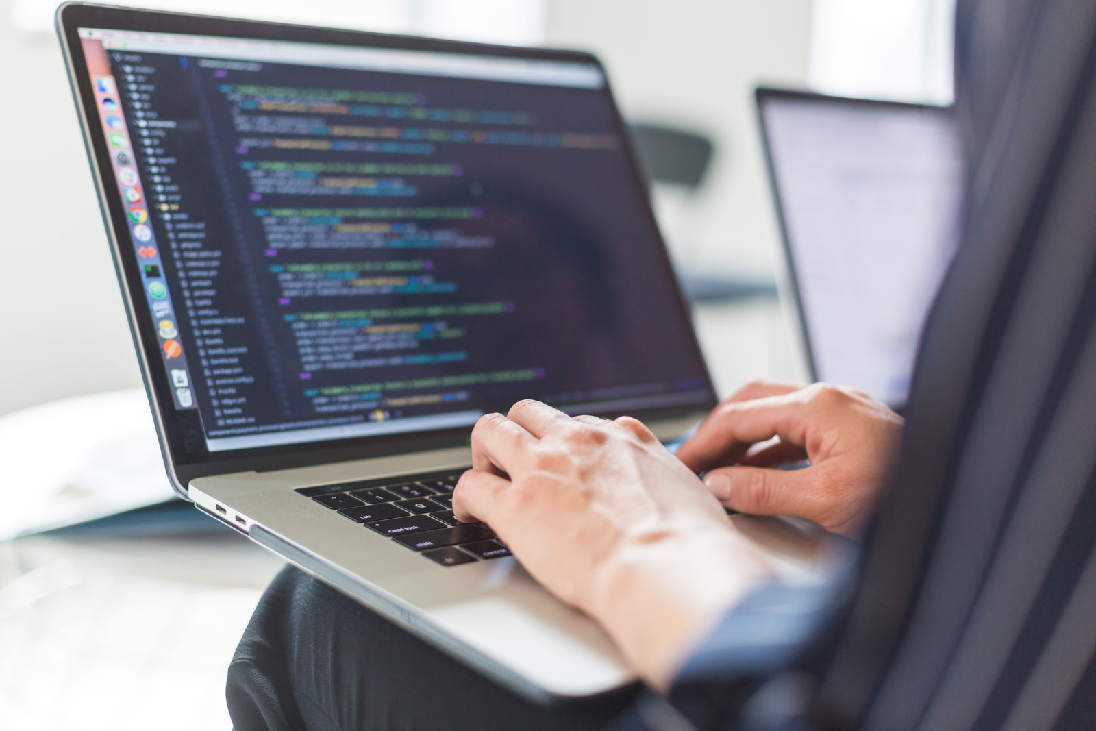 Close-up of hands typing on a laptop showing code